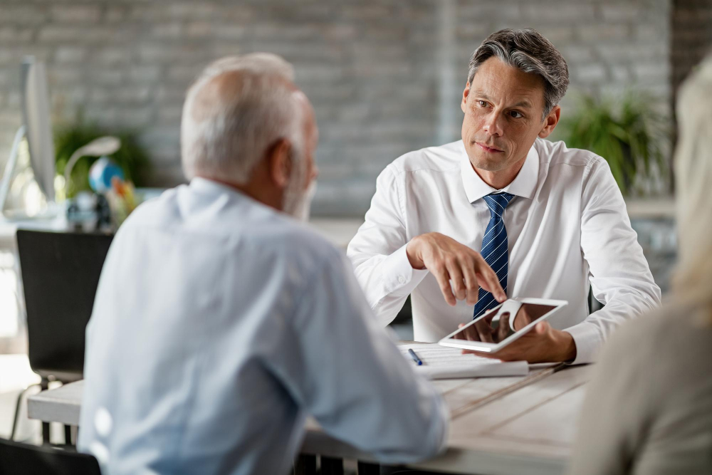 A professional insurance adjuster discussing claims with a client at a desk