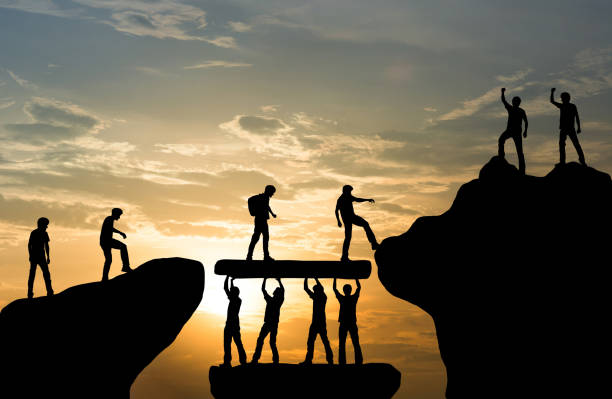 Silhouettes of people working together on a mountain