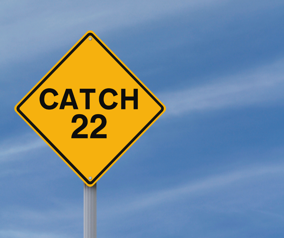 A yellow Catch-22 road sign against a blue sky.